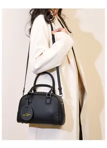 Detail of black lychee grain leather Boston bag with gold logo charm and stitching