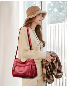 Detail of red soft leather shoulder bag featuring multiple zippers and gold kangaroo logo