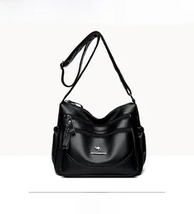 Detail shot of black pebbled leather crossbody bag with multiple zippers and logo