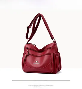 Detail of red textured leather crossbody bag showing multi-zip design and kangaroo logo