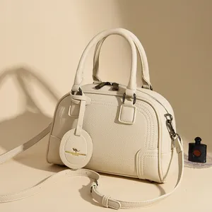 Chic beige lychee leather Boston handbag with dual handles and adjustable shoulder strap