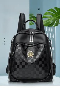 Détail d'un sac à dos en cuir noir avec motif à damier et ferrures métalliques dorées polies