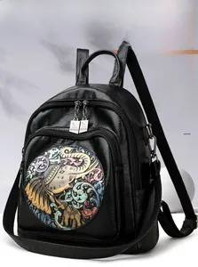 Close-up of black faux leather backpack featuring a colorful elephant embossed pattern