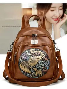 Detailed view of brown leather backpack with colorful elephant embossed pattern and dual zippers