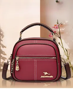 Detail of burgundy lychee grain leather handbag with gold hardware and white stitching