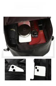 Detail view of black textured leather backpack showing spacious main compartment and pockets