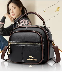 Detail of black litchi grain leather bag with golden logo and brown shoulder strap