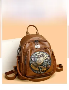 Detail showing vintage brown leather backpack with intricate embossed elephant pattern
