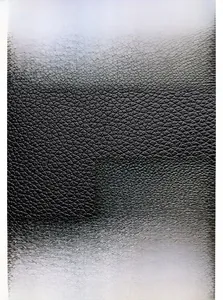 Detail of black lychee grain leather texture with golden kangaroo logo and metal hardware