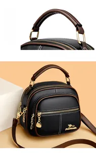 Detailed close-up of textured lychee grain leather and three-layer golden zipper pulls