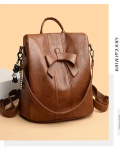 Detail eines braunen Lederrucksacks mit Schleife und Bärenanhänger an der Seite