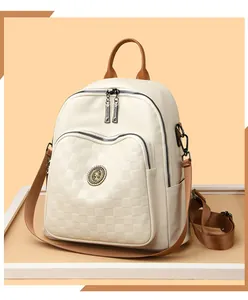 Gros plan sur la poche damier gaufrée et l'emblème en métal du sac à dos en cuir crème