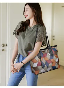 Fashionable large color-block tote bag with geometric patterns worn over the shoulder