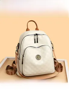 Détail de la texture gaufrée à carreaux et de l'emblème doré sur le sac à dos blanc