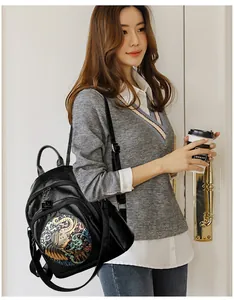 Detail of black leather backpack with colorful ethnic elephant embroidery and metal zipper