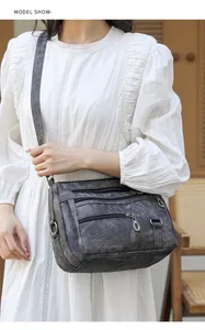Detail view of multi-layer soft grey leather crossbody bag with metallic zippers
