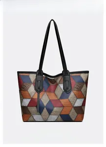 Macro shot of geometric patchwork tote bag showing textured leather and stitching details