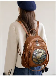 Detail of vintage brown leather backpack featuring an intricate elephant embossed pattern