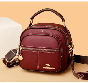 Close-up of wine red lychee pattern leather bag with gold kangaroo hardware and printed strap