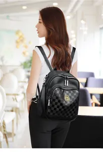 Vue détaillée du sac à dos noir à motif damier avec emblème doré et cuir grainé