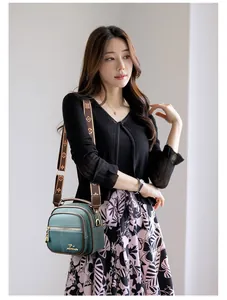 Detail view of dark green leather shoulder bag with ornate floral jacquard strap