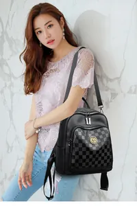 Détail du sac à dos en cuir noir avec poche à damier et emblème métallique doré