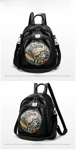 Close-up of black leather backpack featuring colorful artistic elephant embroidery and dual zippers