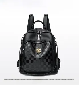 Détail du sac à dos en cuir noir avec motif à damier et logo en métal doré