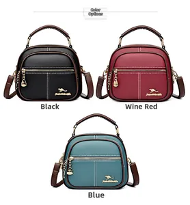 Three leather crossbody bags in black, wine red, and blue with kangaroo logo and gold accents