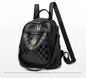Détail du sac à dos noir en cuir grainé avec poche à damier et emblème doré