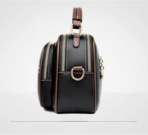 Detail of black litchi leather bag with brown trim and triple golden zip closures