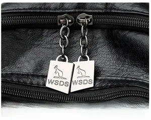 Close-up of litchi textured black leather backpack with branded metal double zippers