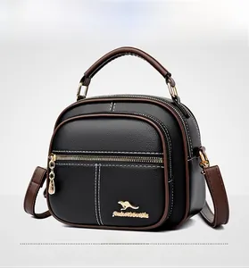 Detail of black pebbled leather handbag with gold kangaroo logo and brown handles