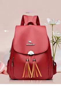 Detail of red leather backpack featuring golden kangaroo logo and tassel pendant