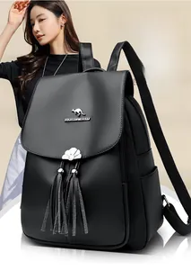 Detail of black pebbled leather backpack featuring silver kangaroo logo and tassel charms