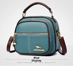 Detail of teal leather crossbody bag with brown handles and gold kangaroo logo
