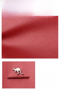 Detail of red pebbled leather bag with a metallic kangaroo logo and silver hardware