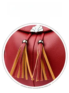 Detail of red lychee grain leather backpack with dual-tone tassels and floral metal clasp
