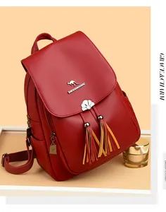 Close-up of red lychee textured leather backpack with gold kangaroo logo and colorful tassel