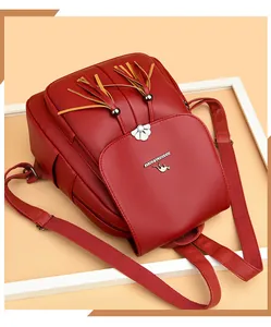 Detail of red lychee grain leather backpack with decorative tassels and silver floral buckle