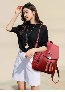 Detail of dark red leather backpack showing metallic kangaroo logo and stylish tassel accents