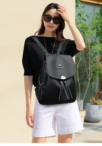 Close-up of black lychee grain leather backpack with metal logo and tassel zippers