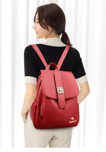 Detail of red leather backpack featuring lychee texture and gold geometric buckle closure