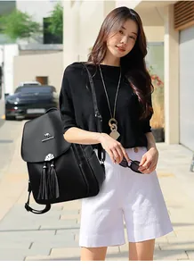 Detail of black leather backpack featuring kangaroo logo and elegant double tassels
