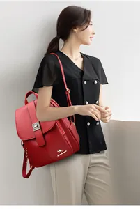 Detail of red leather backpack featuring gold kangaroo logo and metal turn-lock closure