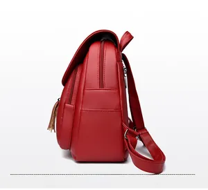 Side view of red faux leather backpack featuring pebbled texture and tassel detail