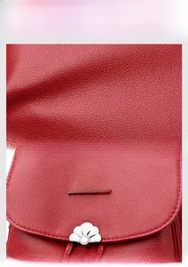 Detail of red pebbled leather backpack with metal kangaroo logo and floral magnetic buckle