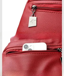 Detail of red leather backpack with metal logo pendant and anti-theft back pocket