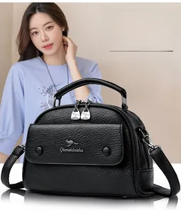 Close-up of black leather handbag featuring textured grain and metallic kangaroo logo