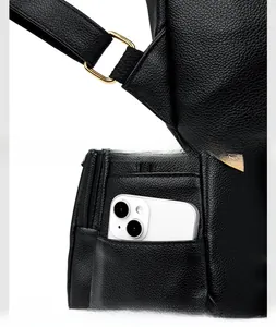 Detail of reinforced shoulder strap stitching and side pocket on black leather backpack
